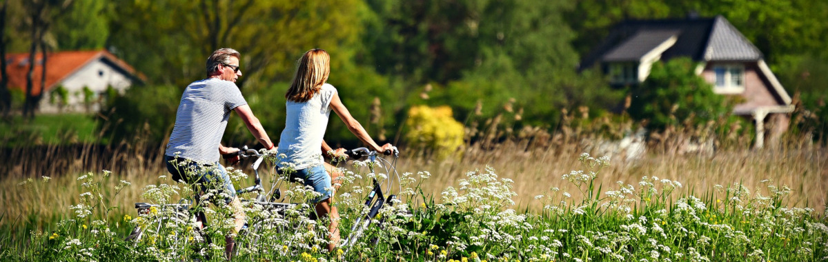 Ein Paar fährt Fahrrad durch sommerliche Landschaft.
